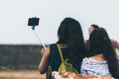 Rear view of woman photographing through mobile phone