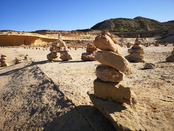 Stack of rocks on sand against sky