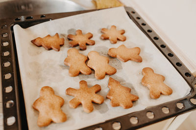 Ready-made homemade hot cookies in shape of christmas tree and man, baking paper and baking tray