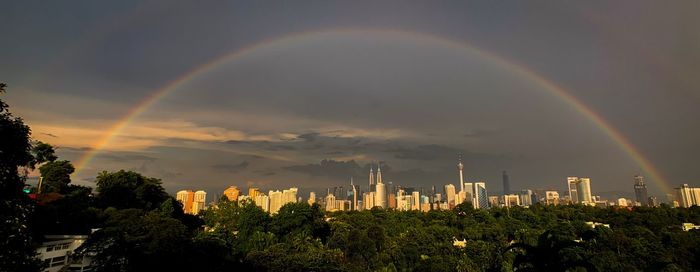 Scenic view of rainbow over buildings in city against sky