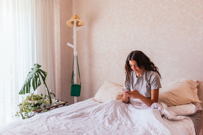 Woman looking away while sitting on bed at home