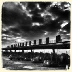 Bridge over river against cloudy sky