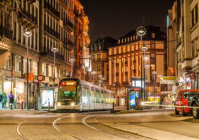Illuminated street amidst buildings in city at night