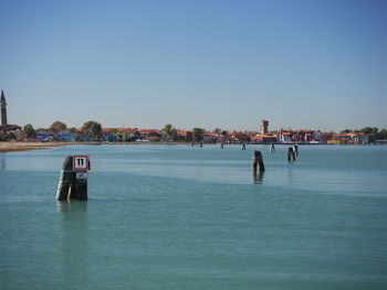 People in sea against clear blue sky