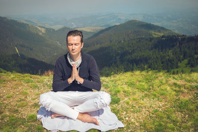 Full length of man practicing yoga on mountain