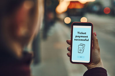 Buying ticket online near bus stop before ride. person paying for ticket using mobile payment app