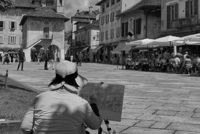 Rear view of people walking on street amidst buildings in city