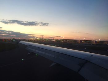 Cropped image of airplane flying over sea at sunset