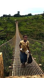 Man sitting on footbridge against sky