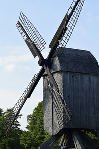 Low angle view of traditional windmill on field against sky