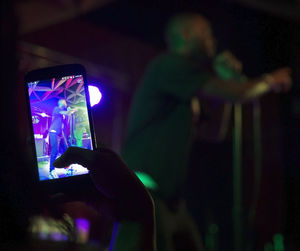 Man photographing illuminated smart phone at music concert