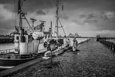 Sailboats moored at harbor against sky