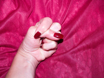 Close-up of woman hand with pink petals on bed