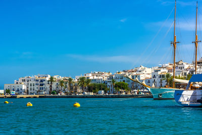 Sailboats moored in sea against blue sky