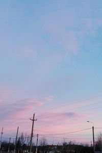 Low angle view of power lines against sky during sunset