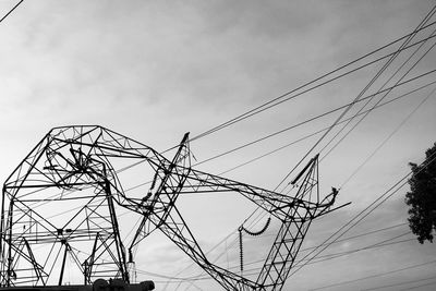 Low angle view of electricity pylons against sky