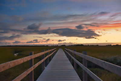 Bridge over empty road against sky during sunset