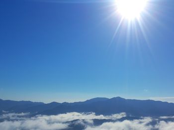 Sun shining through clouds over mountains