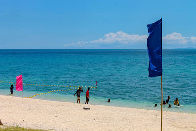 People at beach against blue sky