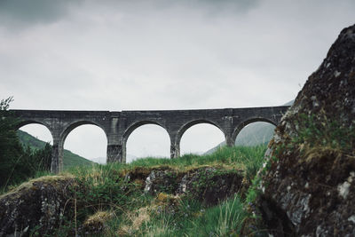 Arch bridge over land against sky