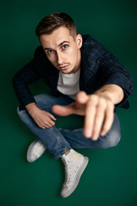 Portrait of young man standing against blue background