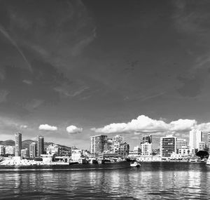 River by city buildings against sky