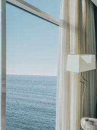 View of sea against clear sky seen through window