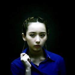 Portrait of young woman against black background