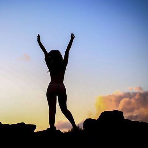 silhouette, sunset, full length, sky, standing, low angle view, arms raised, leisure activity, copy space, arms outstretched, jumping, lifestyles, nature, rock - object, outdoors, orange color, beauty in nature, scenics