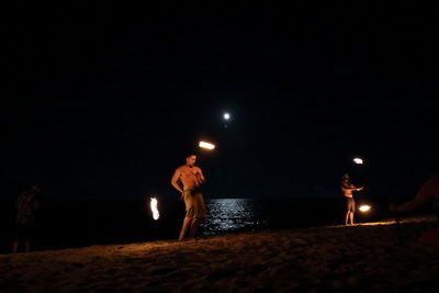 People standing at beach against clear sky at night