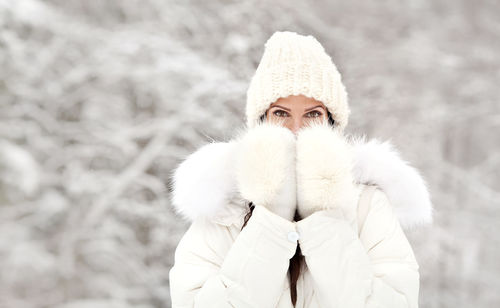 Woman in cold winter weather outdoor. girl wearing warm clothes, white down jacket with fur, beanie