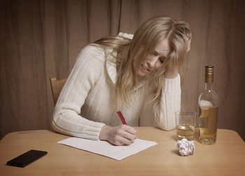 Drunk woman writing on paper at home