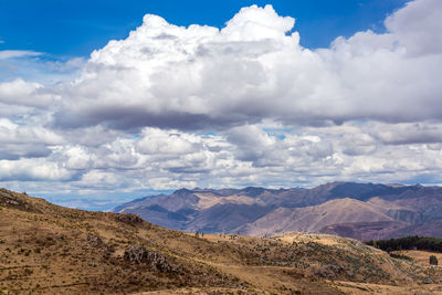 Scenic view of mountains against cloudy sky on sunny day