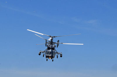 Low angle view of helicopter against clear blue sky