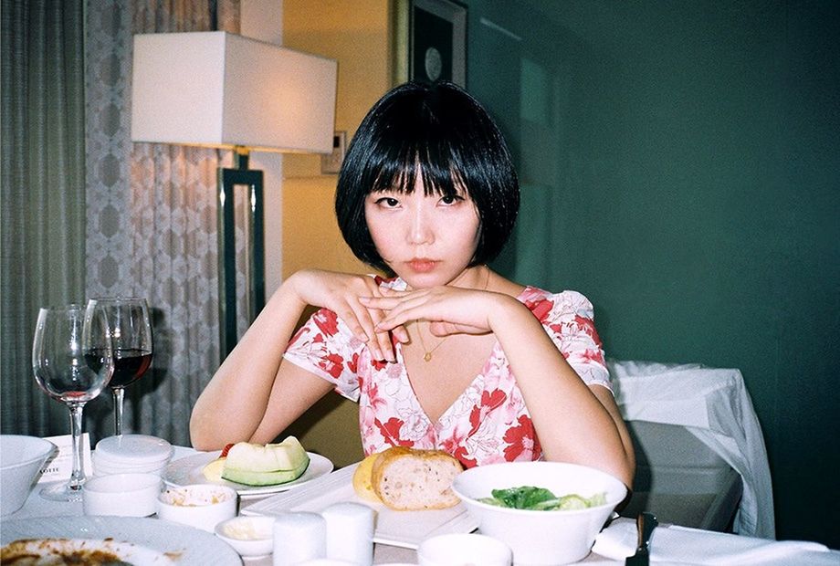 food and drink, sitting, one person, table, food, front view, portrait, indoors, real people, plate, women, drink, black hair, chair, lifestyles, seat, freshness, looking at camera, hairstyle, bangs, glass, hair, beautiful woman, contemplation