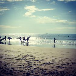 Silhouette people on beach against sky