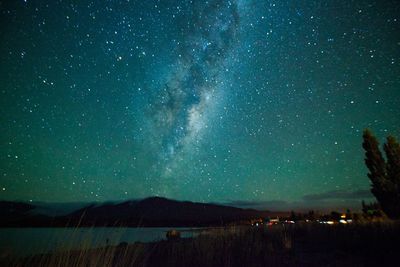 Scenic view of landscape against star field at night