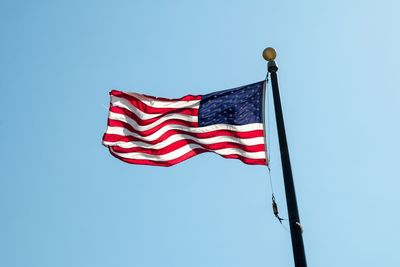 Low angle view of american flag waving against clear sky