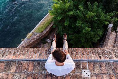 High angle view of man sitting by sea