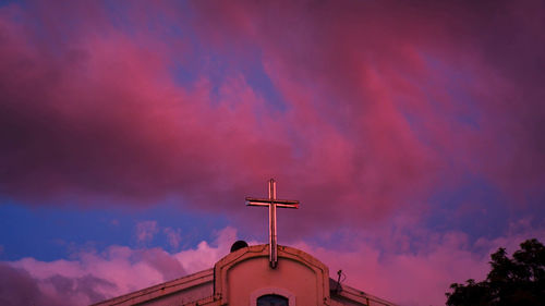 Low angle view of cross on building against sky