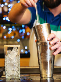 Midsection of person holding ice cream in glass on table