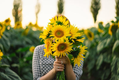 Beautiful young woman with sunflowers enjoying nature and laughing on summer sunflower field.