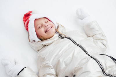 High angle view of smiling girl lying on snow