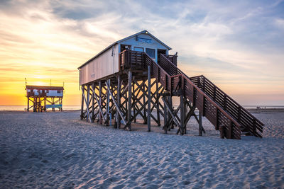 Lifeguard hut on beach against sky during sunset