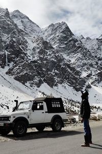 Side view of person on snowcapped mountain against sky