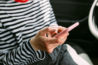 Portrait of a young brunette woman driving in a car using a smartphone