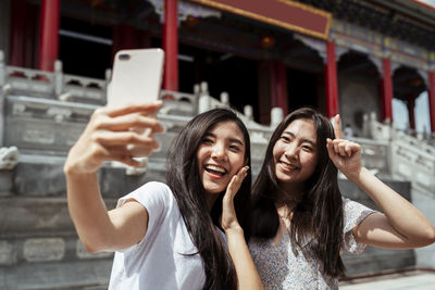 Smiling women vlogging while standing against temple