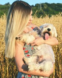 Woman holding dog while standing on field