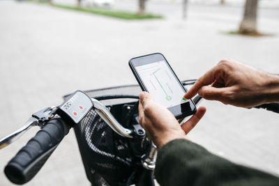 Close-up of man with e-bikeusing smartphone navigation system