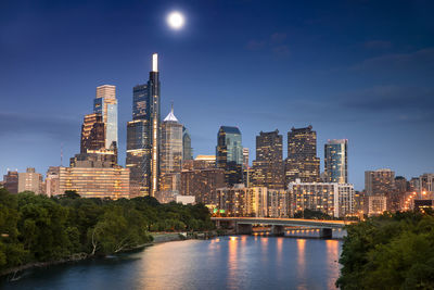 Modern buildings by river against sky in city